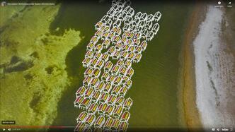 Visualisierung einer Pfahlbau-Siedlung auf einem Luftbild eines Seeufers